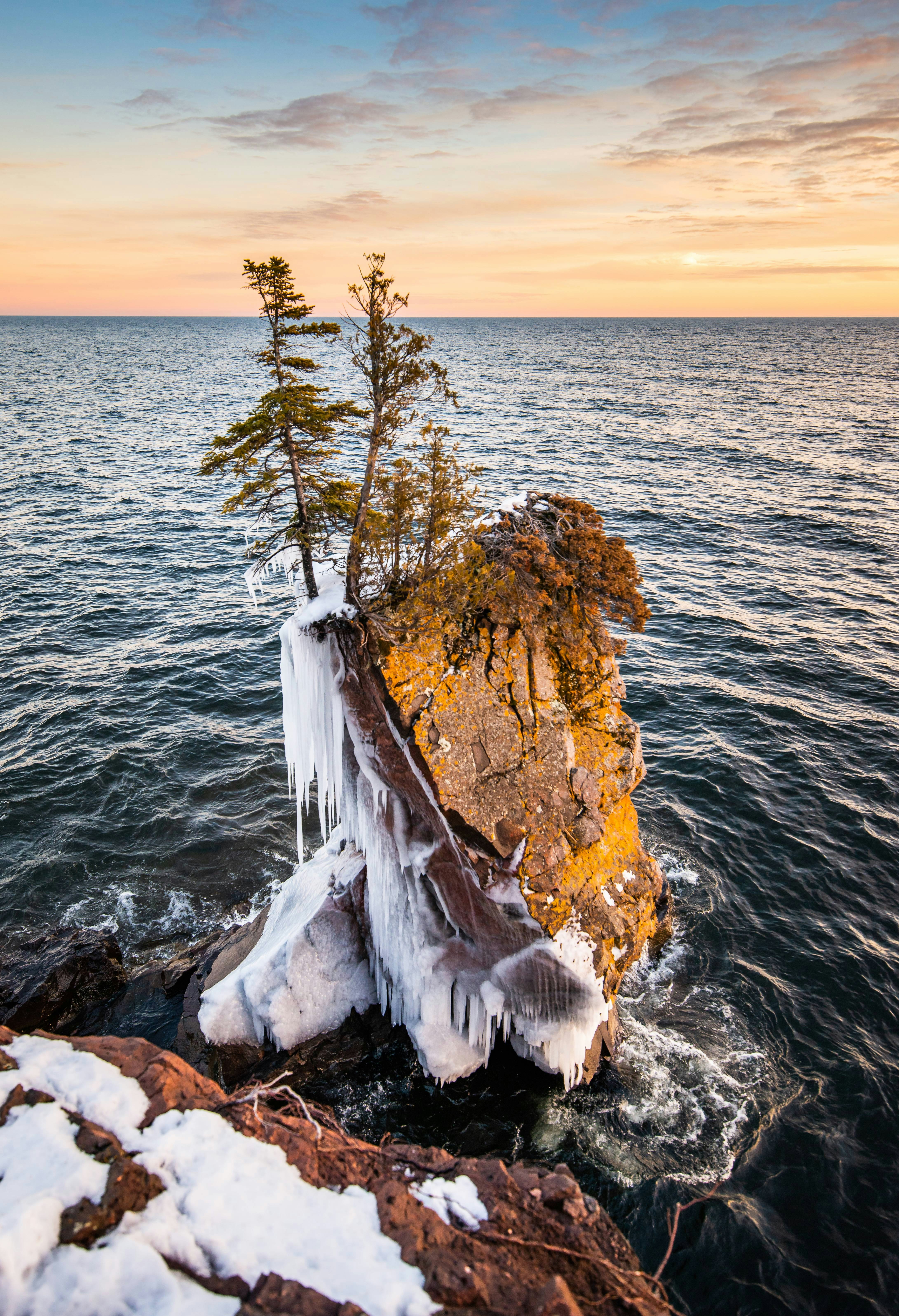 brown and white rock formation beside body of water during daytime